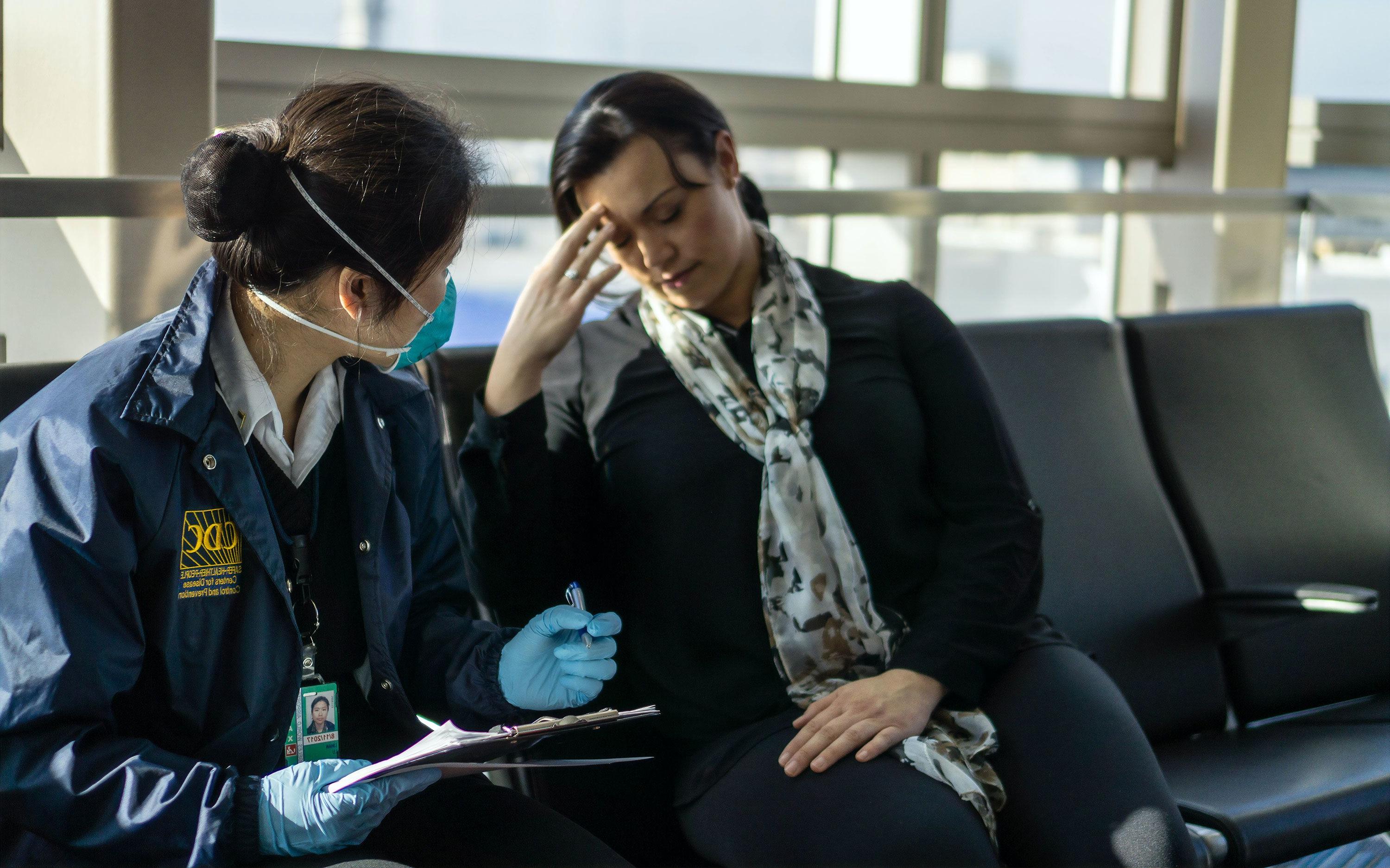 一名妇女在机场与疾控中心工作人员交谈
